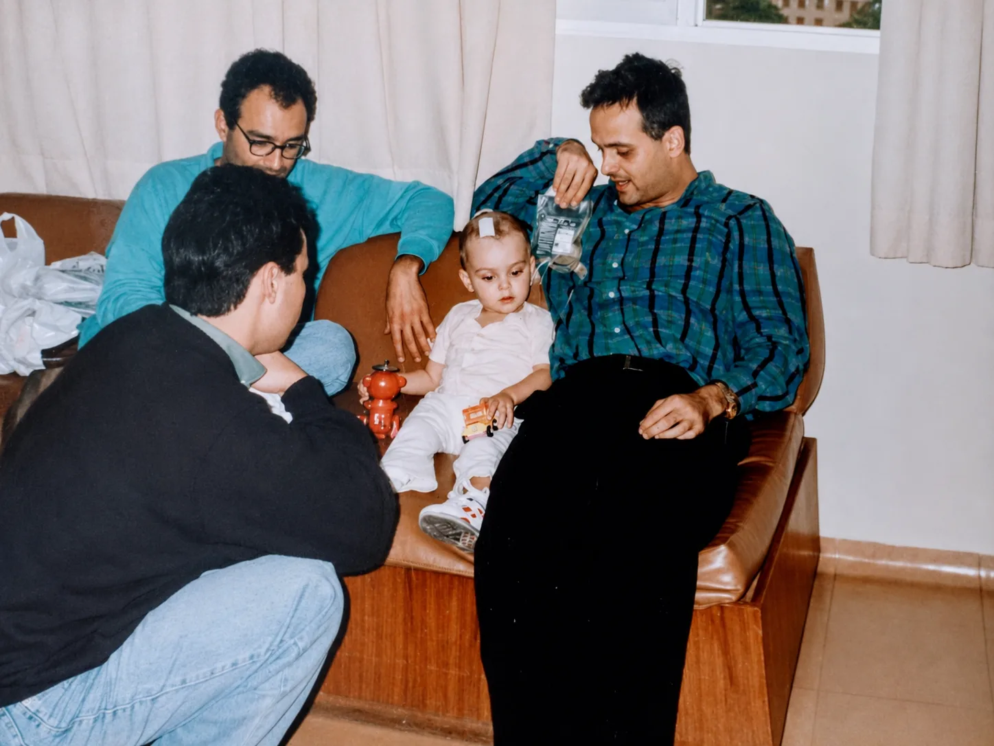Dr. João Guttierrez, ainda bebê, no colo de um familiar, cercado por outros parentes durante a internação.